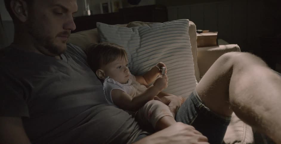 A man sits on the couch with his young son