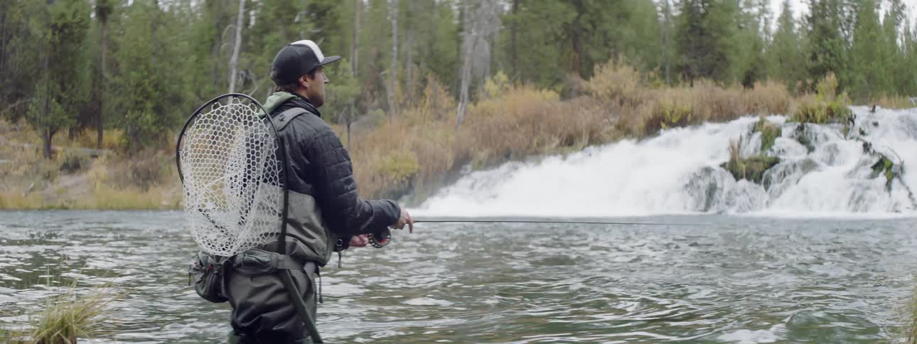Someone is standing in the middle of a river fly fishing