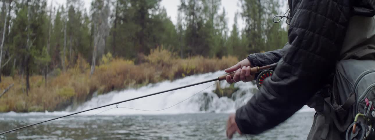 A fisherman fishes in a stream