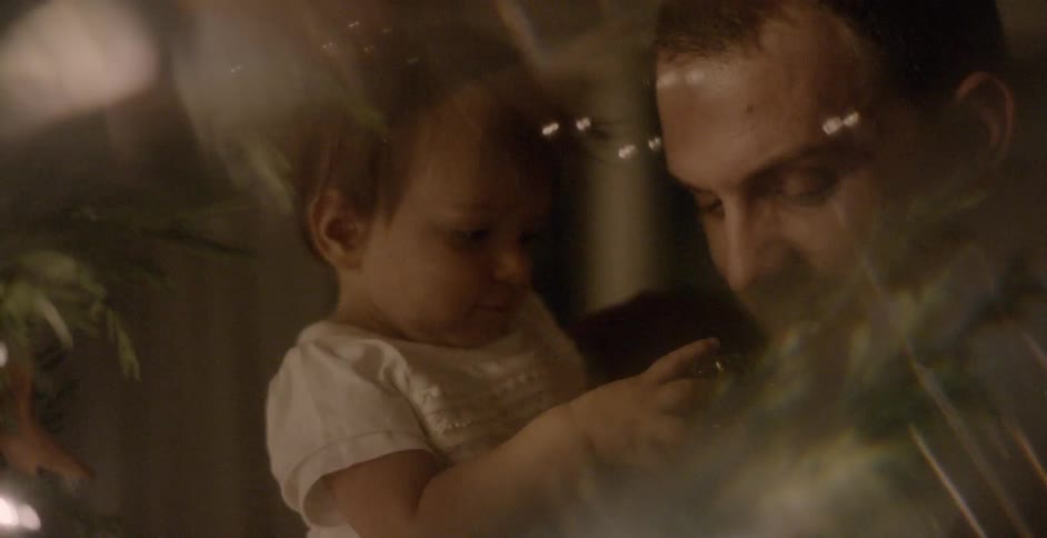 A father holds a baby next to a christmas tree