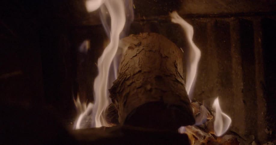 Logs are added to a burning fire in a fireplace