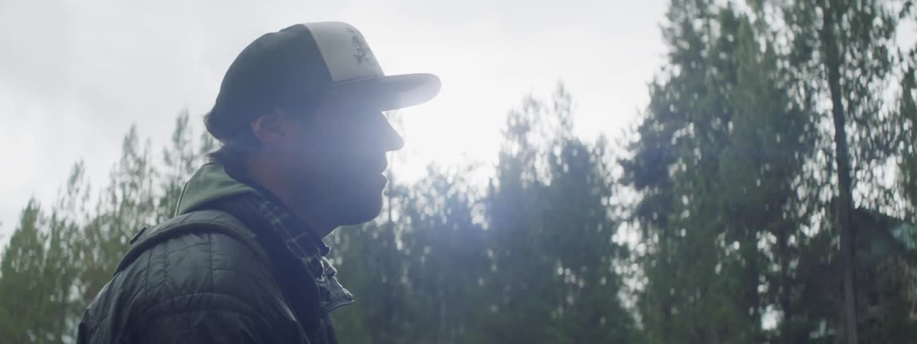Man waves a fishing pole outside near trees