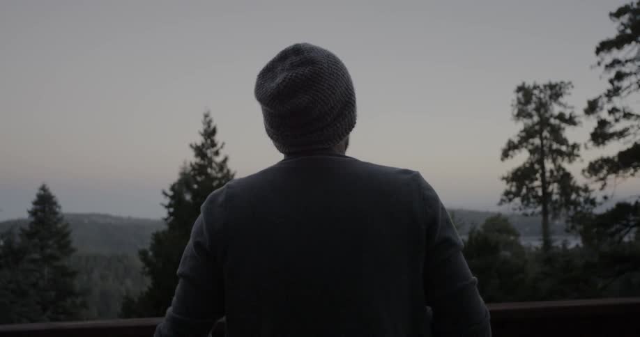 A man walks out onto a cabin balcony