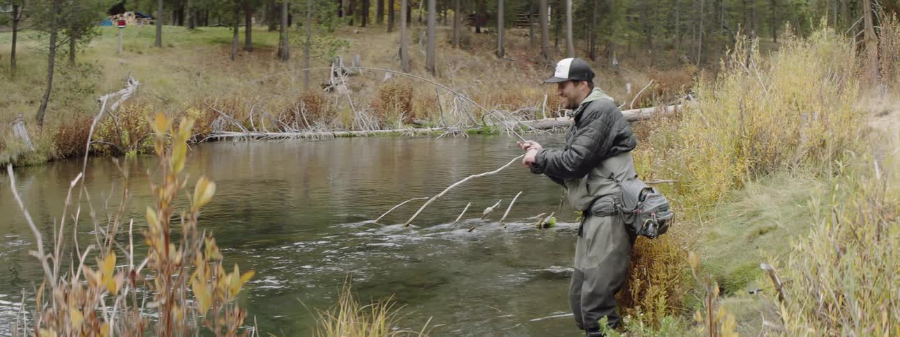 A man is fly fishing in the stream