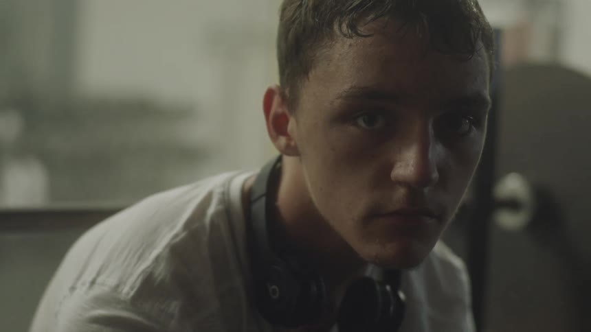 Man sitting staring at the camera wearing headphones around his neck