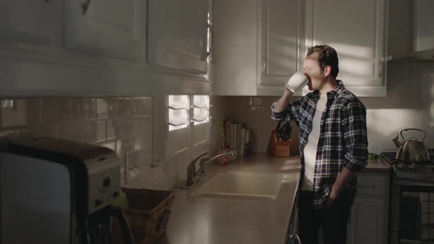 Man sips coffee in a kitchen