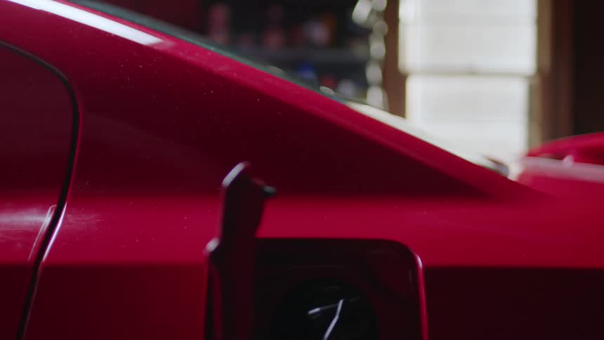 Someone is opening and closing the gas cap on their red muscle car
