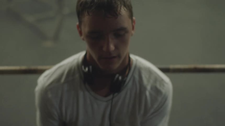 Man wearing headphones around his neck lifting weights