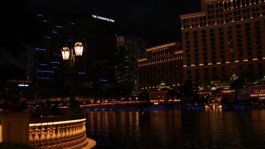 People stand around outside by the buildings at night