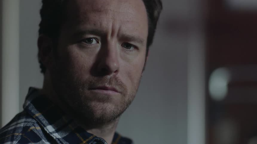 A man in a flannel shirt turns and stares