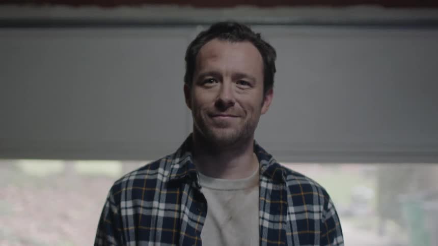 Man smiling and nodding while standing in a garage