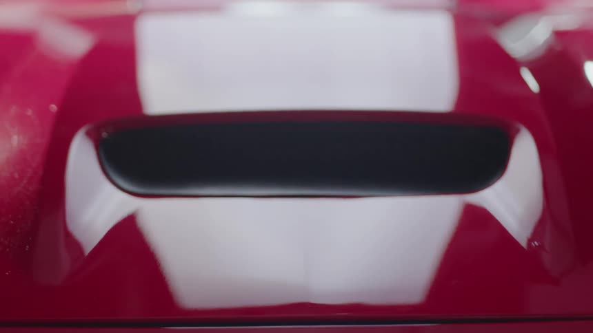 The hood of a red car closes
