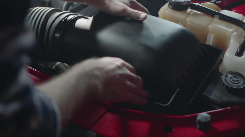 A man is installing an filter in his vehicle's engine