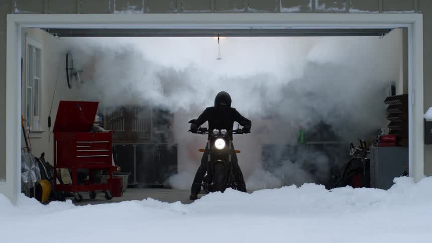 A person is running their motorcycle in the garage