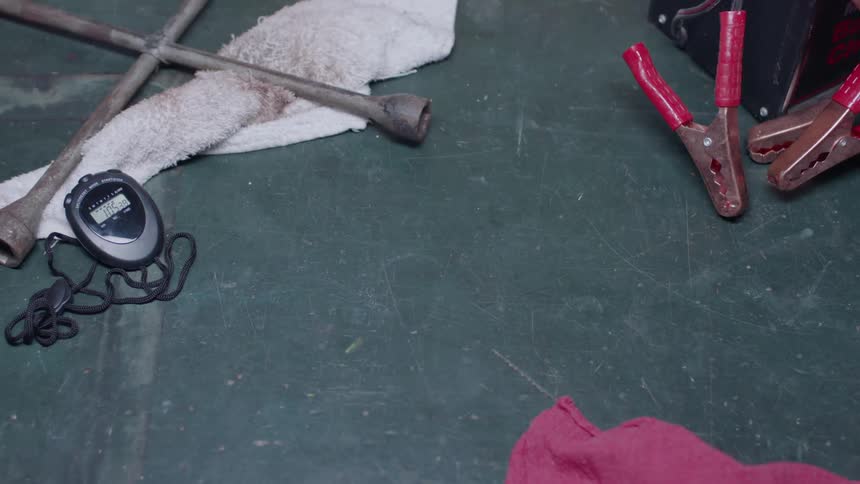 The ground is covered with tools and a stopwatch