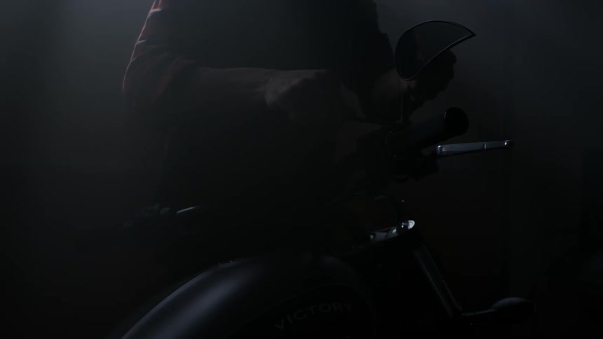 A man uses a wrench on a motorcycle then walks away