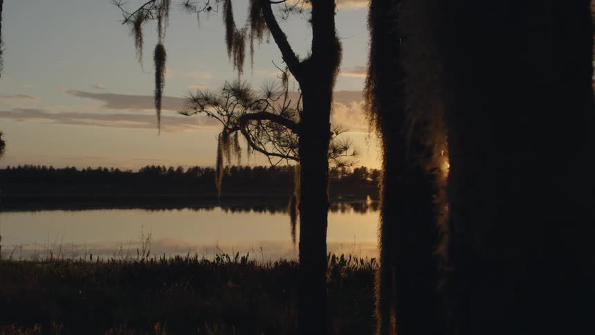 The sun sets and shines on a lake