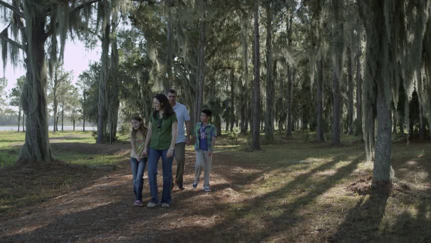 A family are walking on a dirt path in a park during the day