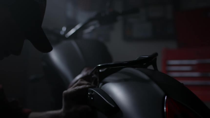 Man working on a motorcycle in a dark garage