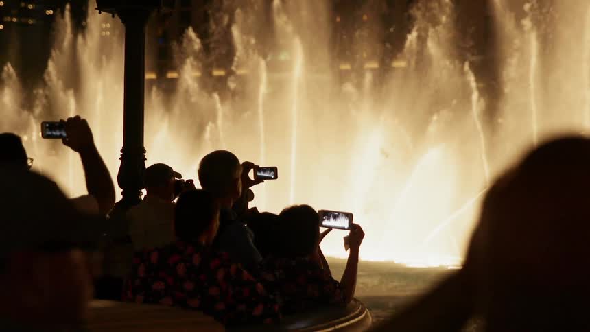 People record and look out at spraying fountains