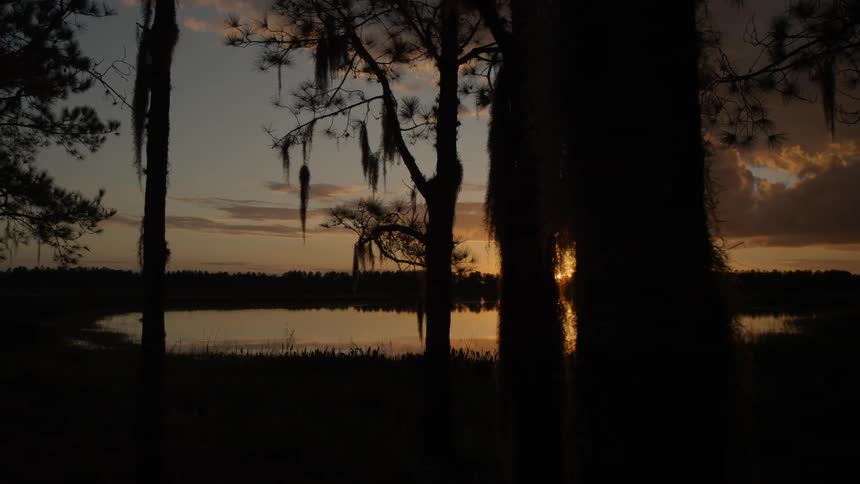 The sun sets and shines on a lake
