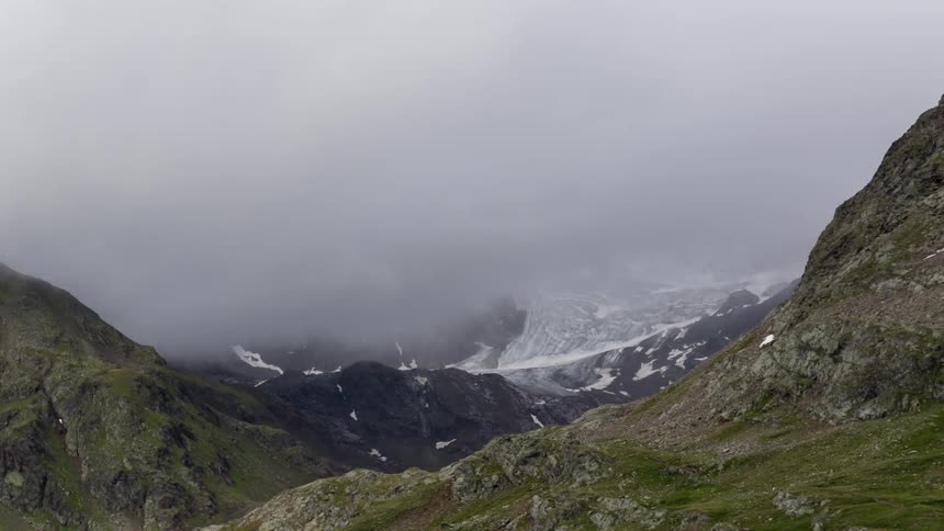 Storm clouds are moving over a glacier in mountain valley