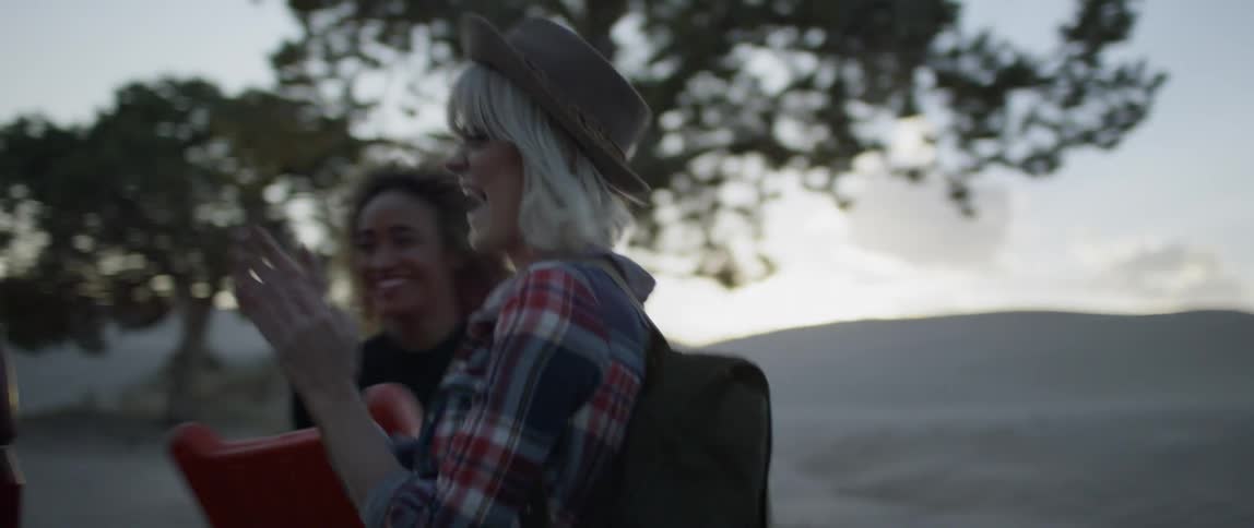 A group of women unload camping equipment and laugh