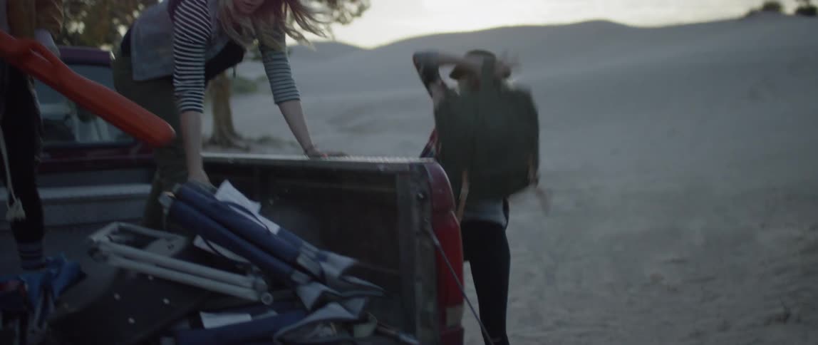 A group of women unload camping equipment from the back of a truck