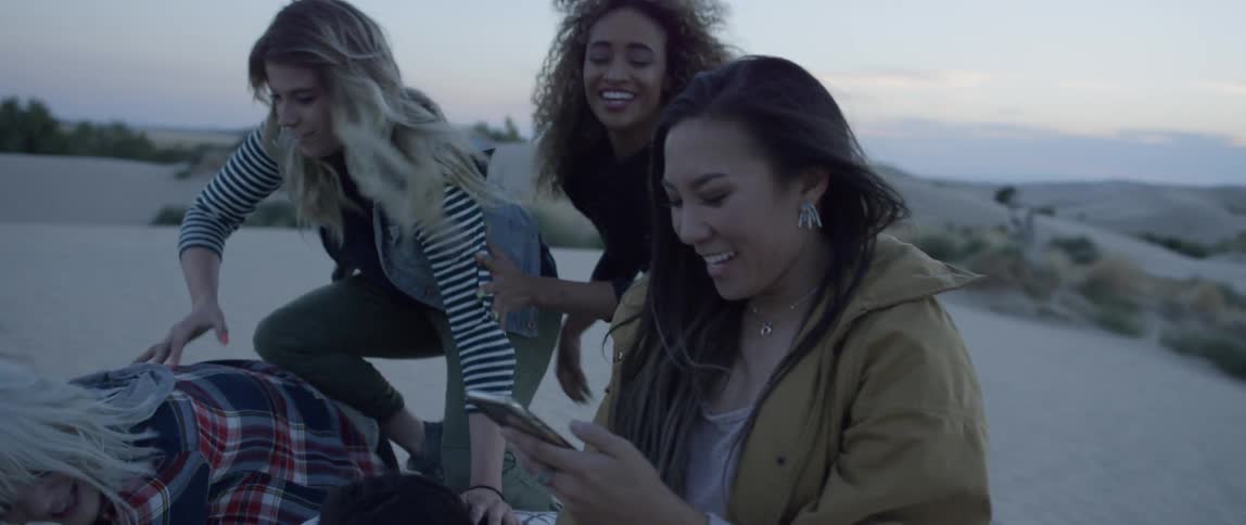 A group of women laugh while taking a photo in a desert