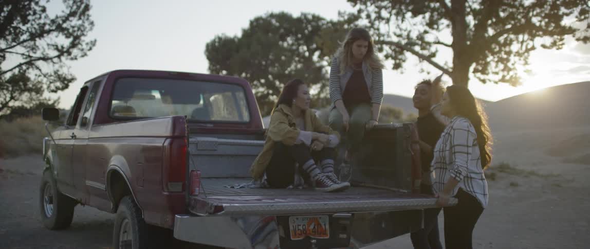 A group of women converse at the back of a truck