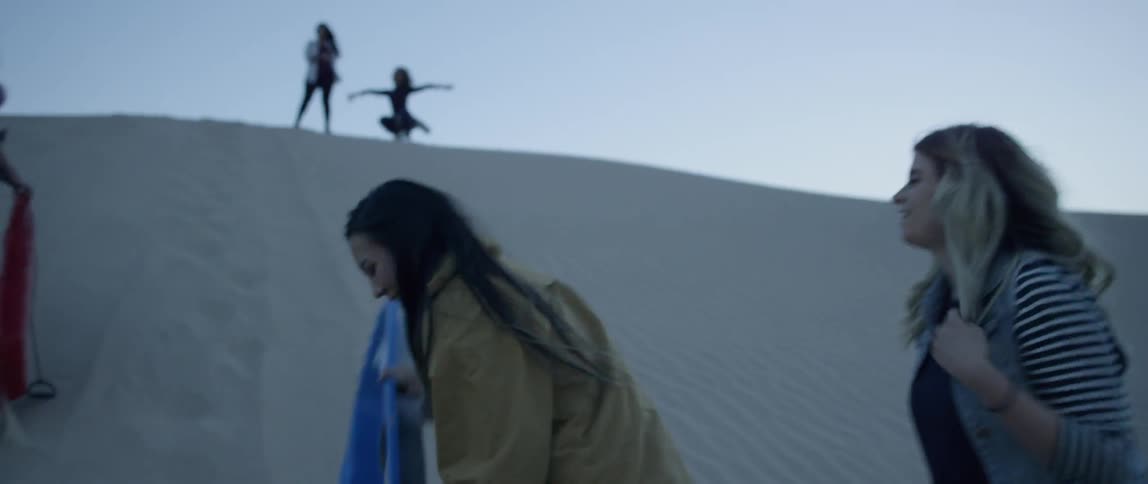 Women carry sleds up a sand hill