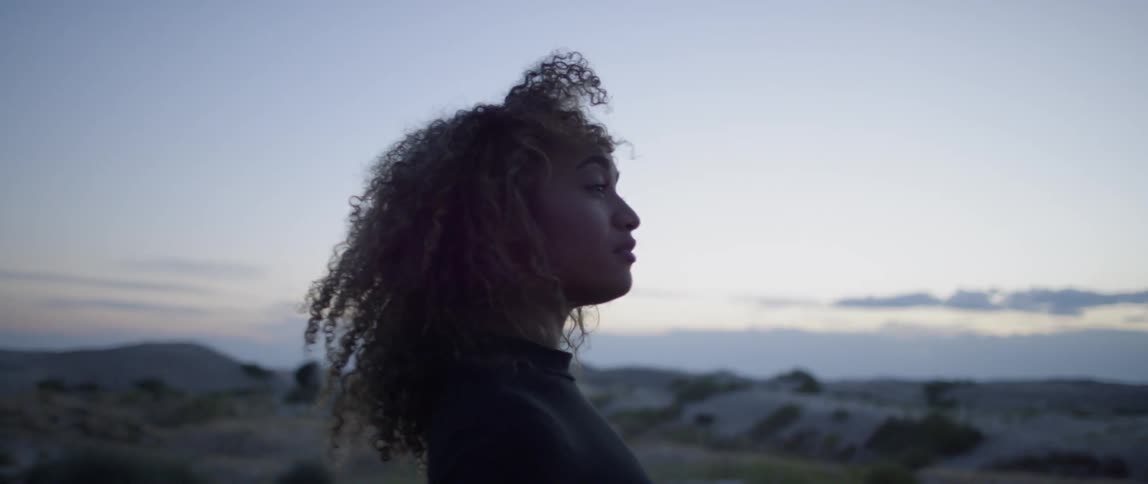 Woman stands outside in the desert at sunset