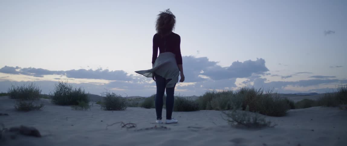A woman stands in the breeze and looks around