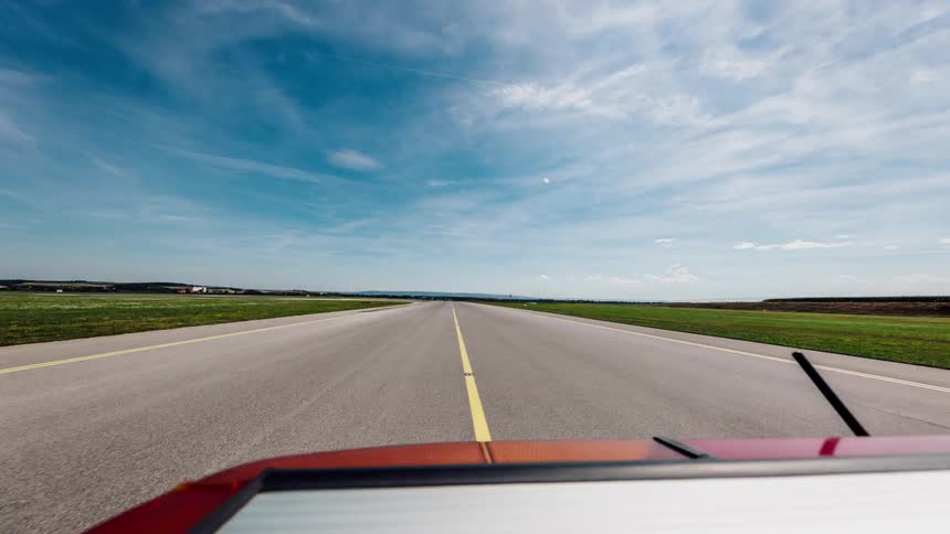 A person drives a car down a long road