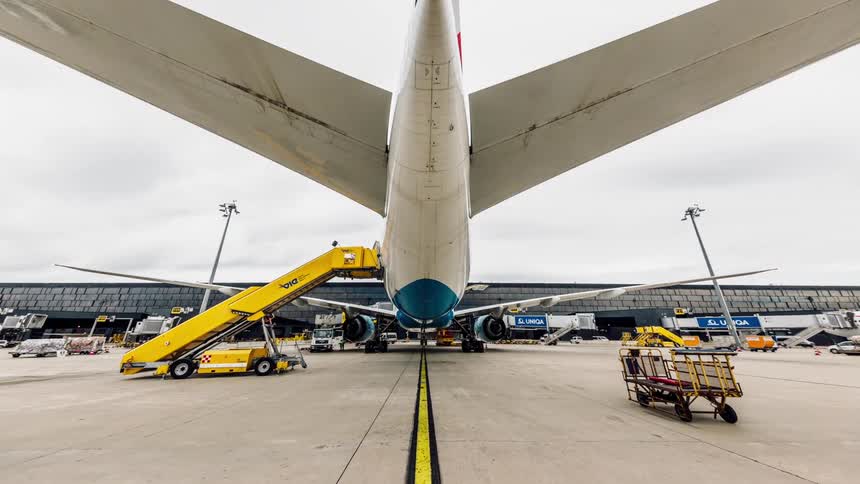 Activity buzzes around a plane at an airport during the day