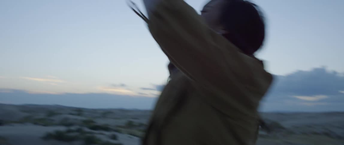 Woman throws a football to another woman outside in the desert in the evening
