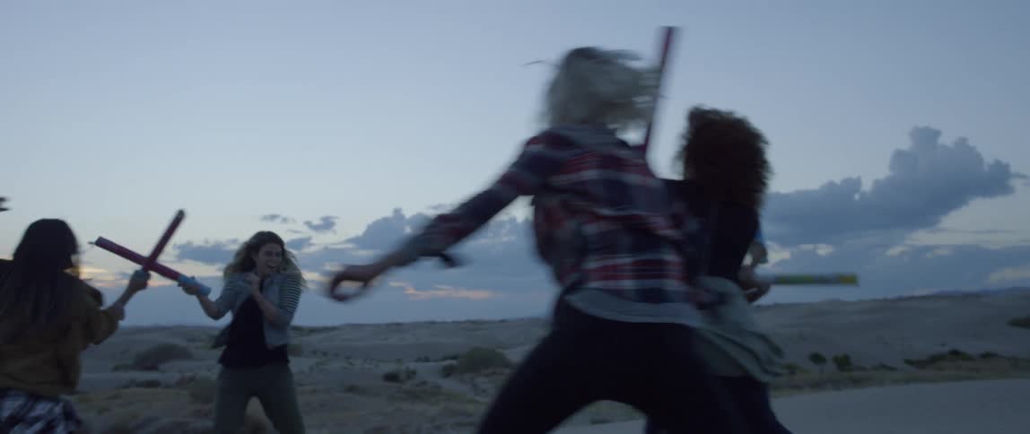 A group of women play fight with plastic tubes