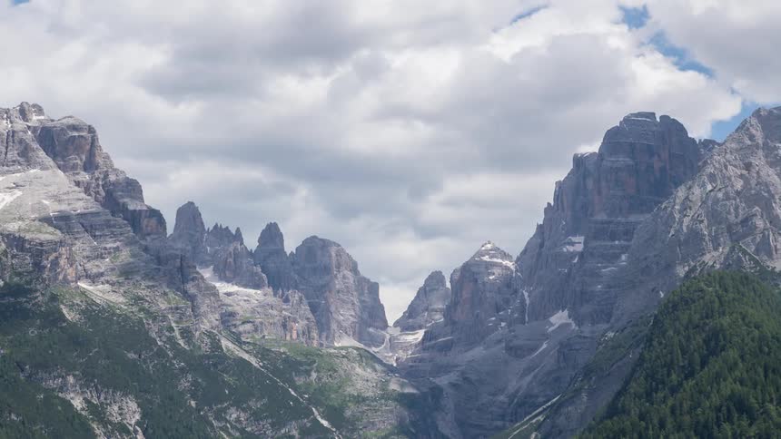 Cloud shadows pass over rocky mountain peaks in the Dolomites