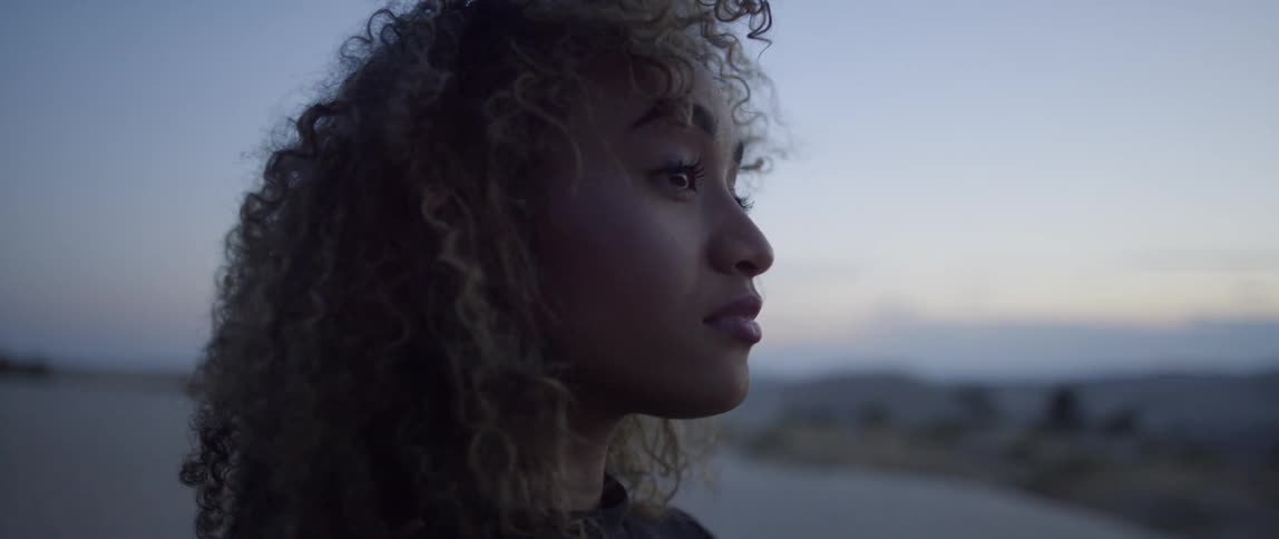 Woman stands outside in the desert at sunset