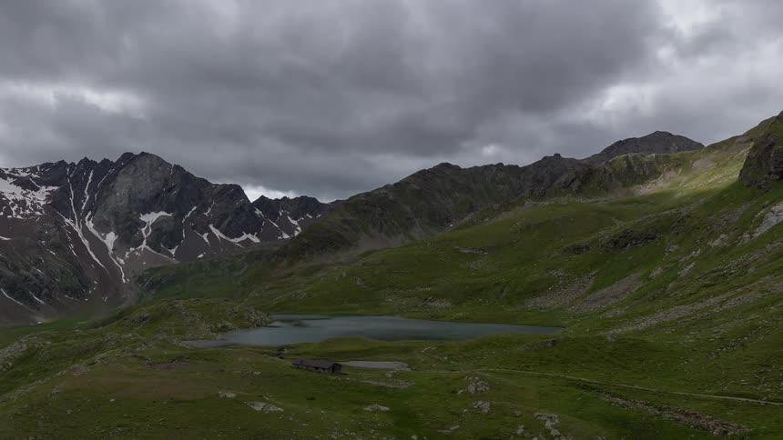 Time lapse of clouds moving over a green valley with a mountain in the background