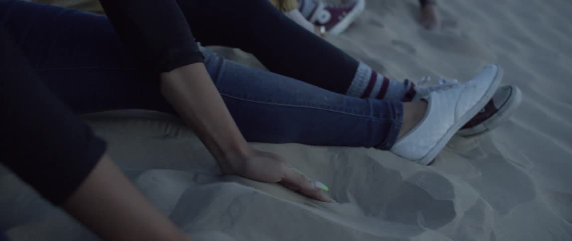 Group of women sit outside playing in the sand