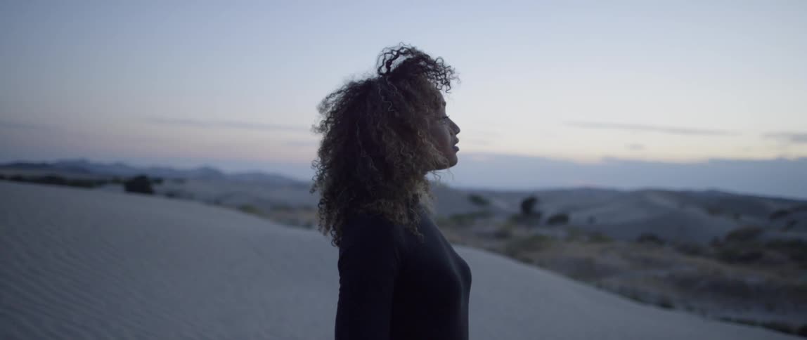 Woman walks in a desert at sunset