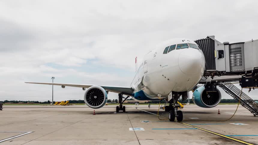 Vehicles drive past a parked plane on the runway