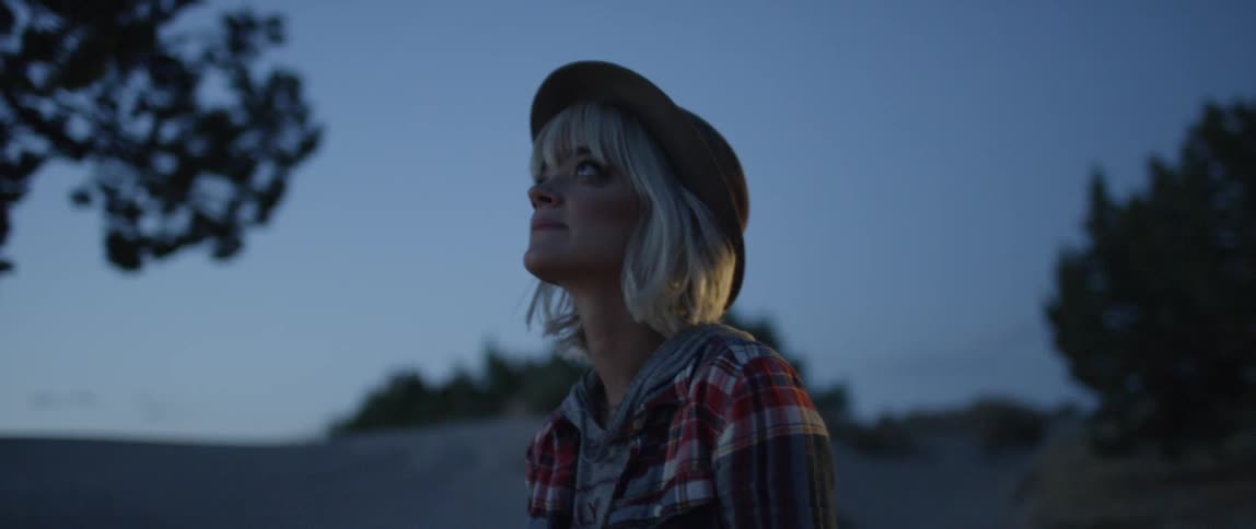 A woman walks in a desert at dusk