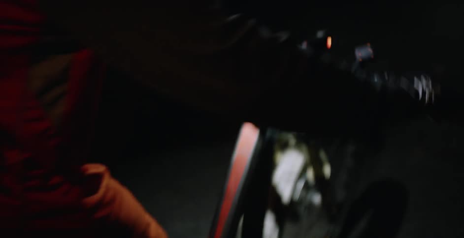A bicyclist rides on a sidewalk at night
