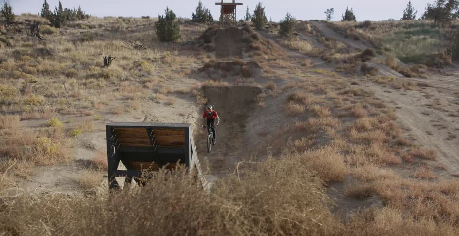 A bicyclist jumps off a ramp and spins in the air