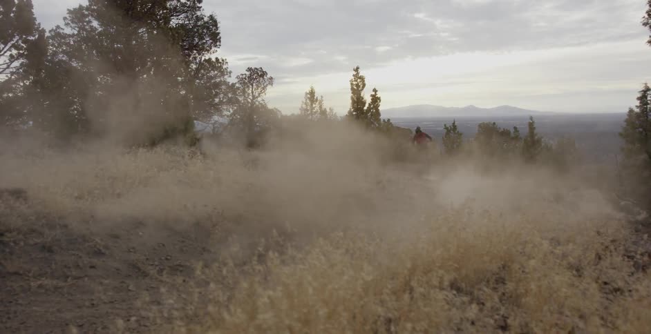 A bicyclist rides on a dirt path in the mountains
