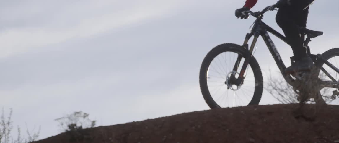 A man is riding a mountain bike on a trail on a cloudy day