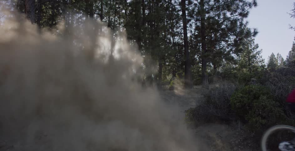 A bicyclist skids and kicks up dirt on a course