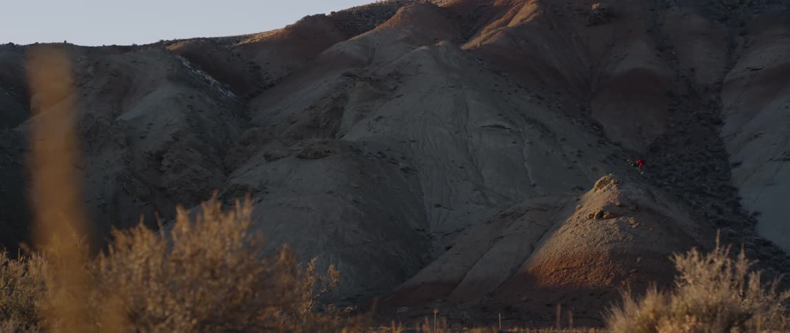A bicyclist jumps and does a trick on a mountainside at sunset
